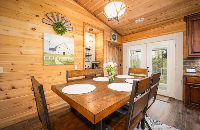 dining space featuring french doors, dark wood-style floors, vaulted ceiling, visible vents, and wood walls