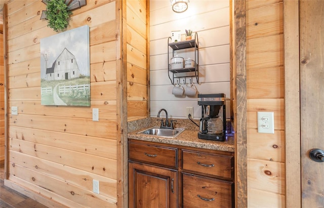 bar featuring wet bar, wood walls, and a sink