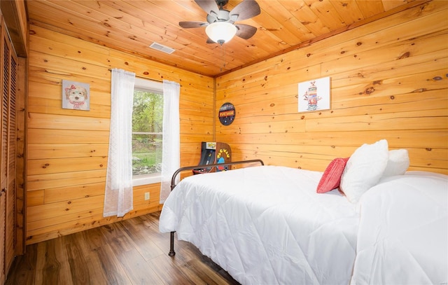 bedroom featuring a ceiling fan, wood finished floors, wood ceiling, wood walls, and visible vents
