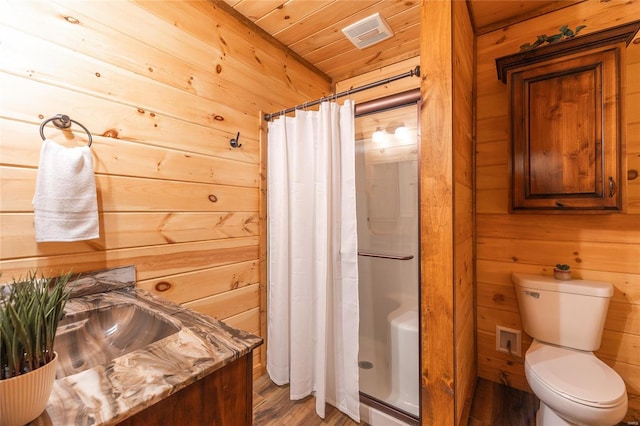 bathroom featuring a shower stall, a sink, wooden walls, wooden ceiling, and toilet