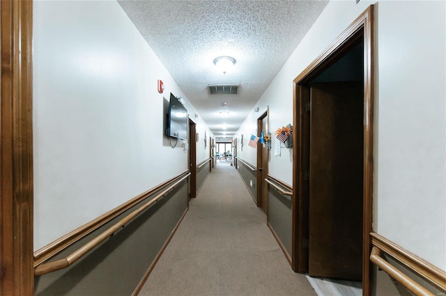 corridor featuring light colored carpet and a textured ceiling