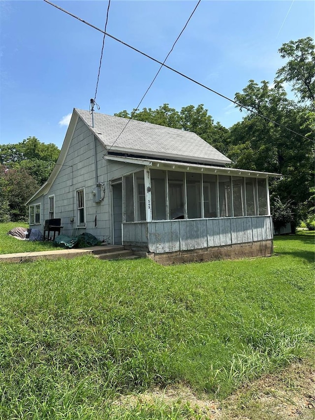 view of side of home with a sunroom and a lawn