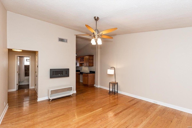 unfurnished living room featuring a textured ceiling, high vaulted ceiling, ceiling fan, and light wood-type flooring