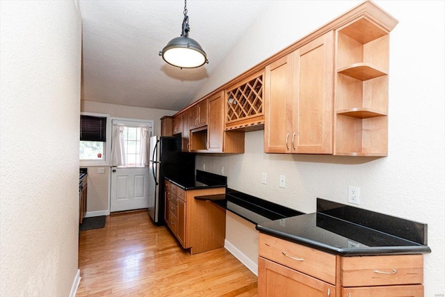 kitchen with vaulted ceiling, stainless steel refrigerator, light hardwood / wood-style flooring, and pendant lighting