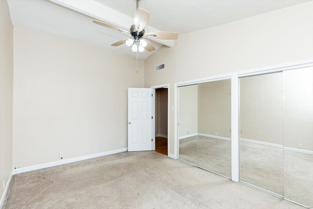 unfurnished bedroom featuring ceiling fan, high vaulted ceiling, multiple closets, and carpet flooring