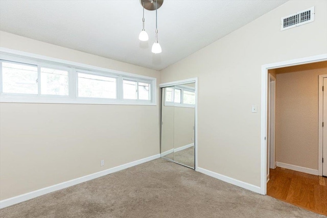 unfurnished bedroom featuring carpet floors, vaulted ceiling, and a closet