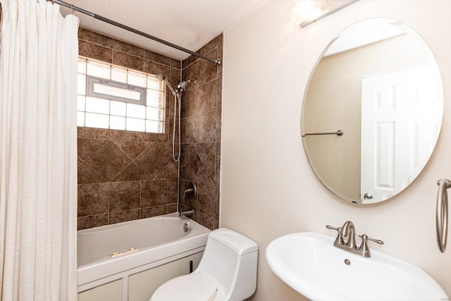 full bathroom with sink, a textured ceiling, shower / bath combo, and toilet