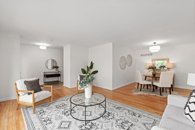 living area with baseboards, wood finished floors, and visible vents