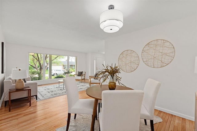 dining space featuring baseboards and light wood finished floors