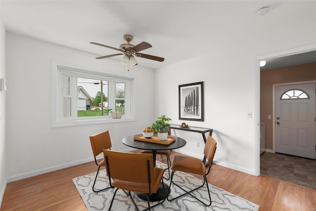 dining area with light wood-style floors, baseboards, and a ceiling fan