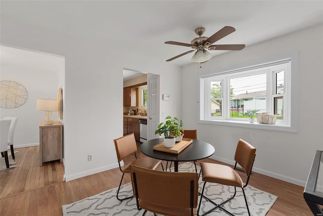 dining room with baseboards, light wood finished floors, and ceiling fan