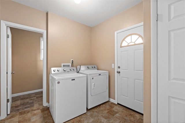 washroom featuring washing machine and clothes dryer, baseboards, stone finish floor, and laundry area