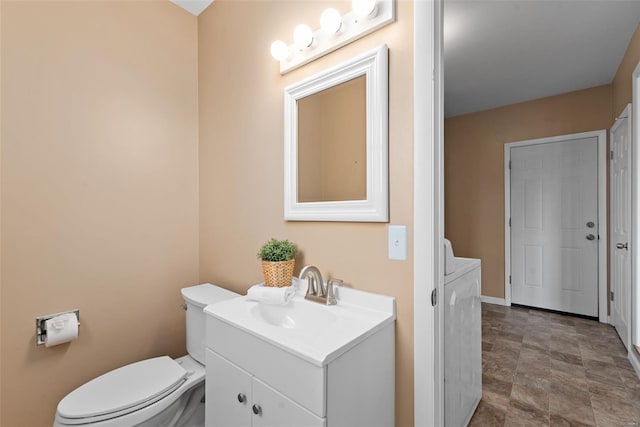 half bath with vanity, baseboards, toilet, and washer / clothes dryer