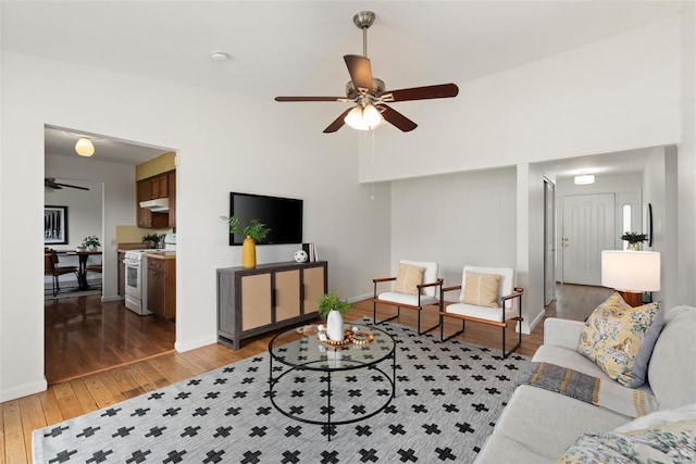 living room with a ceiling fan, baseboards, and light wood finished floors