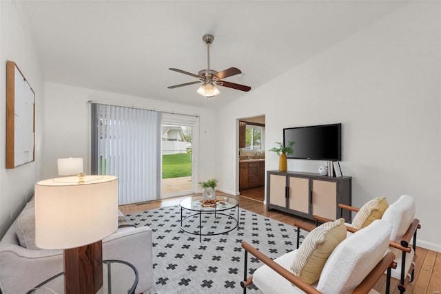living area with wood finished floors, baseboards, ceiling fan, and lofted ceiling