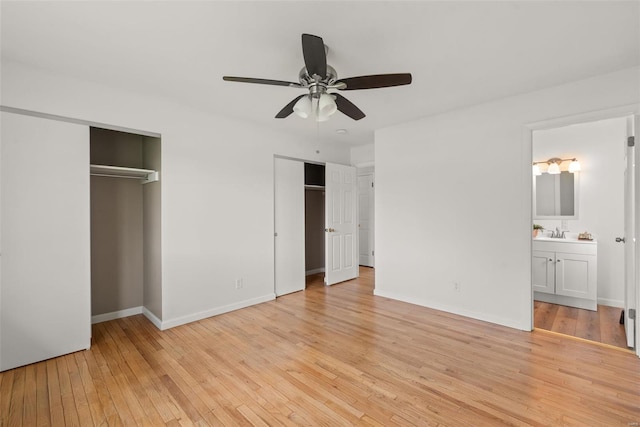 unfurnished bedroom featuring two closets, baseboards, ensuite bathroom, ceiling fan, and light wood-type flooring