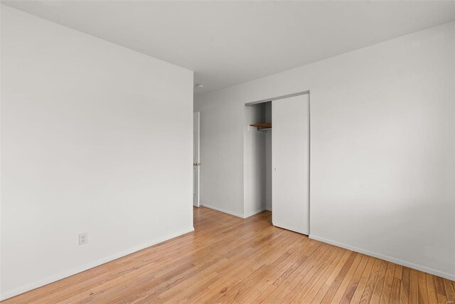 unfurnished bedroom featuring light wood-type flooring, baseboards, and a closet