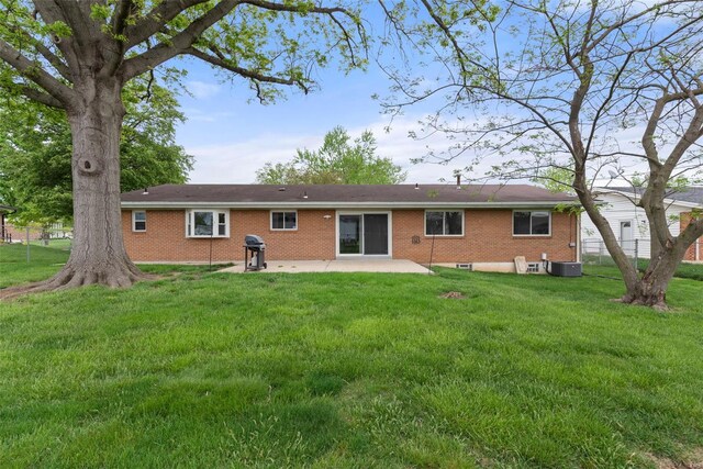 rear view of property featuring fence, brick siding, a patio area, a lawn, and central air condition unit