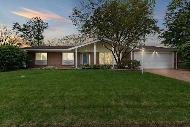 view of front of home with brick siding, a front lawn, an attached garage, and driveway