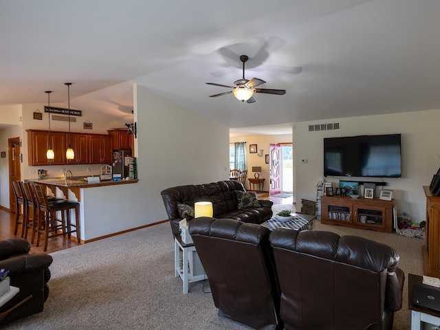 living room featuring lofted ceiling, carpet flooring, visible vents, baseboards, and a ceiling fan