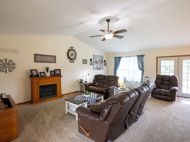 carpeted living room with a glass covered fireplace, vaulted ceiling, baseboards, and ceiling fan