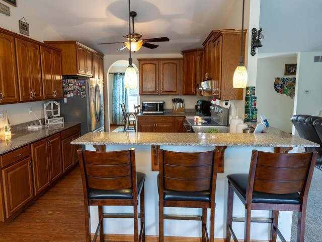 kitchen with appliances with stainless steel finishes, light stone countertops, ceiling fan, and dark wood-type flooring