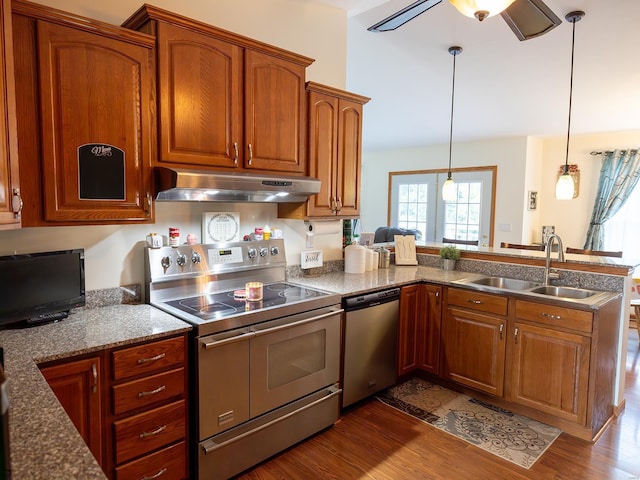 kitchen featuring stainless steel appliances, dark wood-type flooring, a sink, a peninsula, and under cabinet range hood