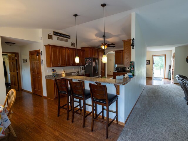 kitchen featuring kitchen peninsula, ceiling fan, dark hardwood / wood-style floors, stainless steel appliances, and vaulted ceiling