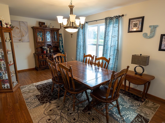 dining room featuring baseboards, wood finished floors, and an inviting chandelier