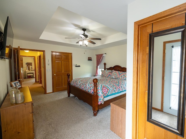 bedroom featuring carpet, a tray ceiling, ceiling fan, and baseboards