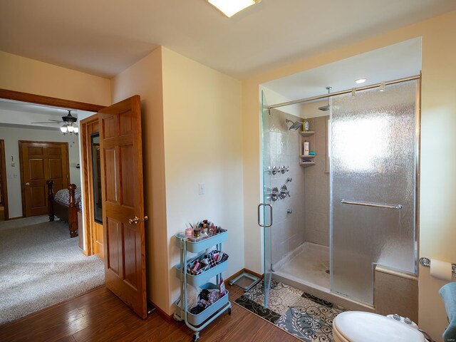 bathroom featuring walk in shower, hardwood / wood-style flooring, toilet, and ceiling fan