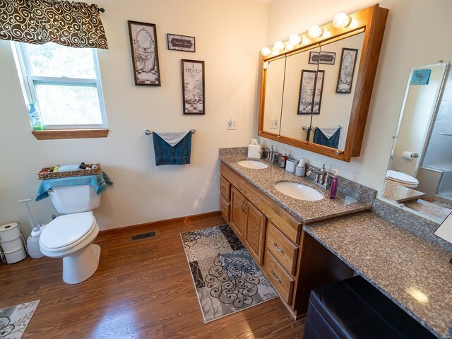 bathroom with dual vanity, toilet, and wood-type flooring