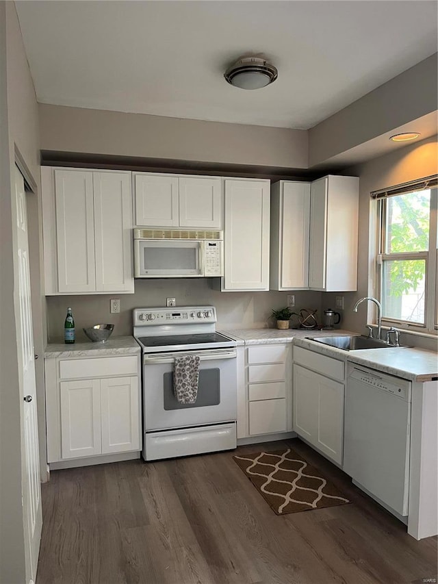 kitchen featuring white cabinets, white appliances, dark hardwood / wood-style floors, and sink