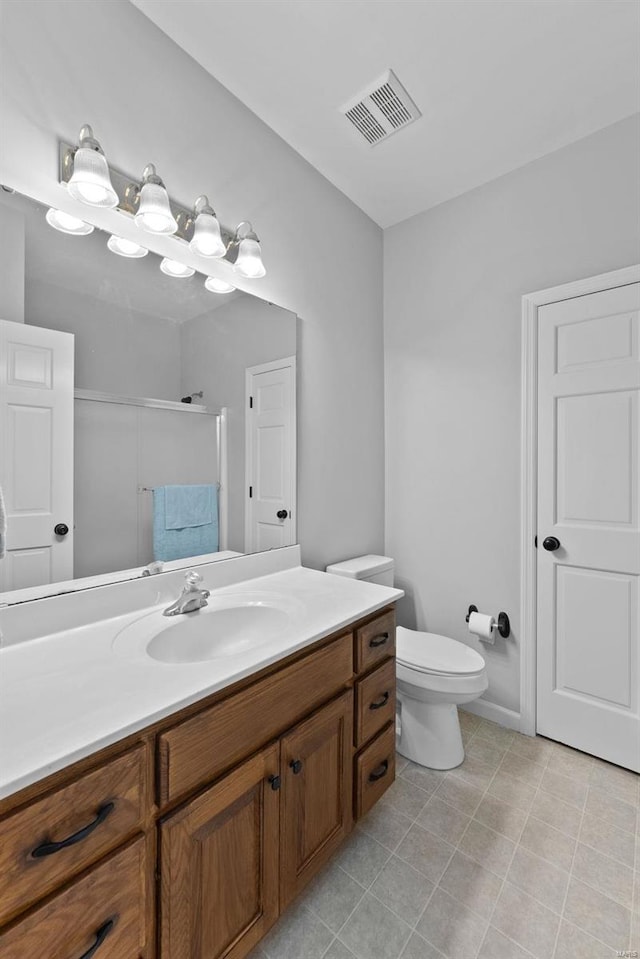 bathroom featuring tile patterned floors, vanity, toilet, and an enclosed shower