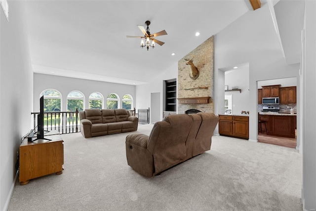 living room with ceiling fan, light colored carpet, high vaulted ceiling, and a brick fireplace