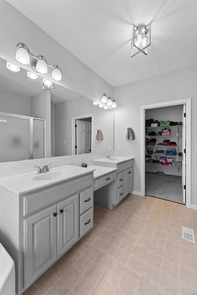 bathroom featuring a shower with door and vanity