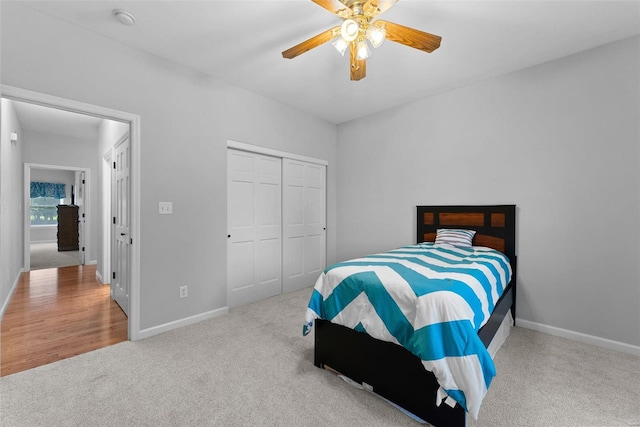 bedroom with light colored carpet, ceiling fan, and a closet