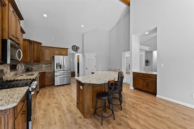 kitchen featuring a kitchen island, high vaulted ceiling, sink, stainless steel appliances, and light stone countertops