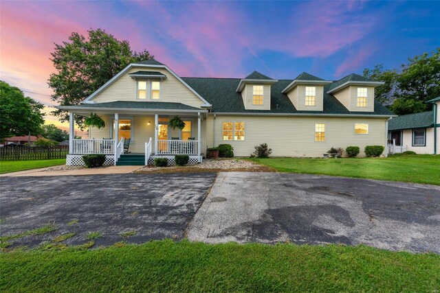 view of front of property featuring covered porch and a yard