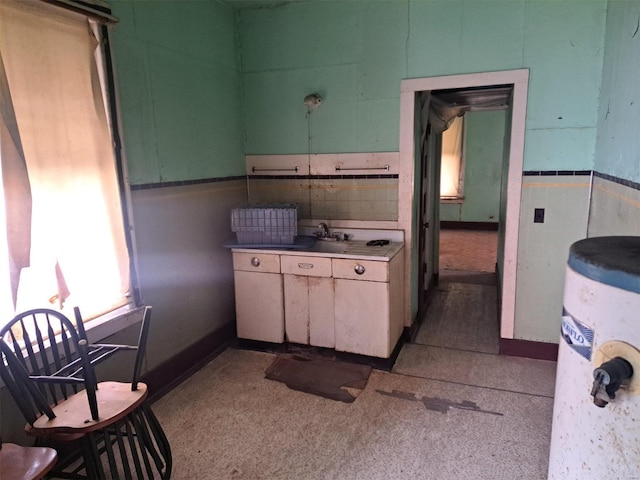 kitchen featuring green cabinets, water heater, and sink