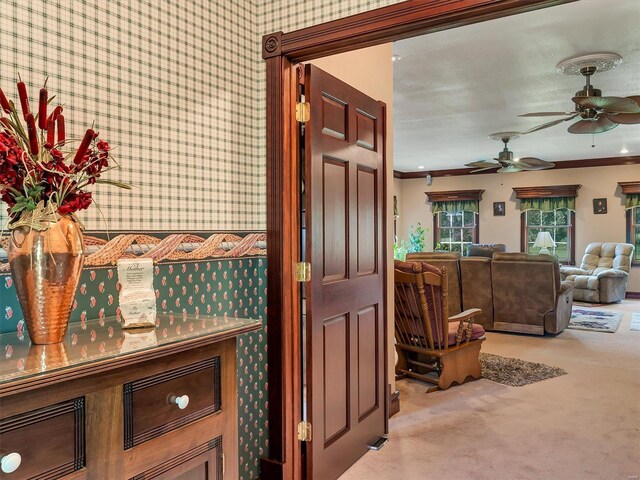 interior space with crown molding, light carpet, and ceiling fan