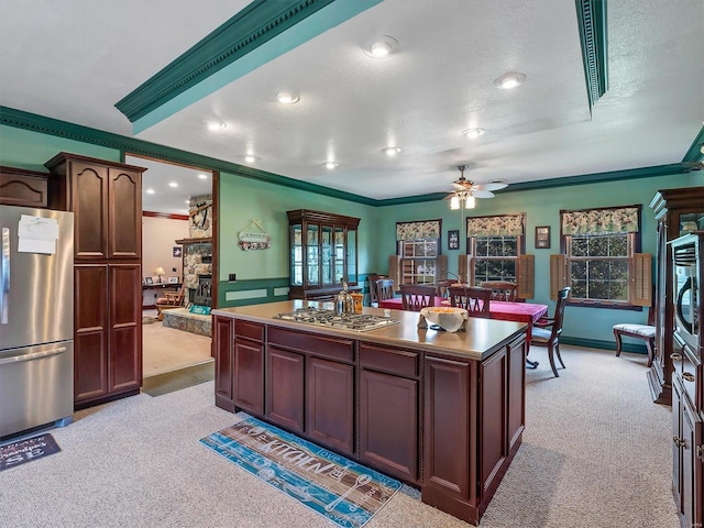 kitchen with a center island, light colored carpet, stainless steel appliances, crown molding, and a textured ceiling