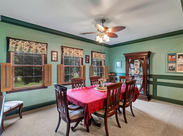 carpeted dining room with ceiling fan and ornamental molding