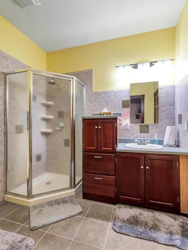 bathroom with walk in shower, vanity, tile patterned flooring, and tile walls