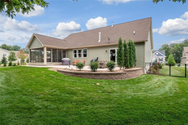 rear view of property with a sunroom and a lawn