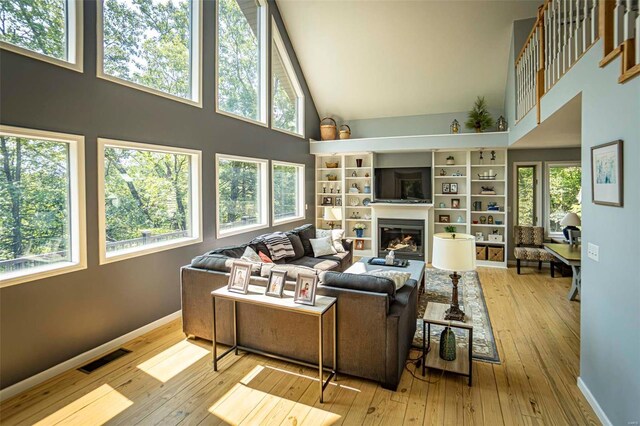 living room featuring a healthy amount of sunlight, a high ceiling, and light hardwood / wood-style floors