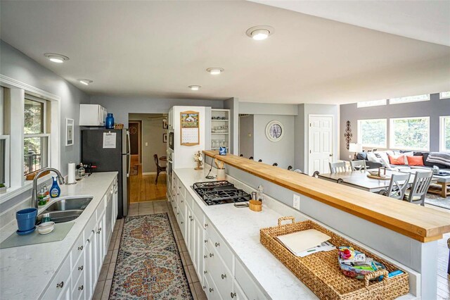 kitchen with white cabinets, light wood-type flooring, stainless steel appliances, sink, and butcher block counters