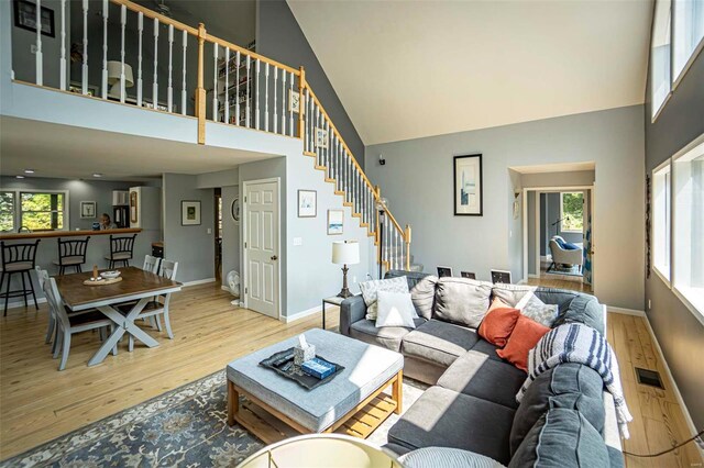 living room featuring a wealth of natural light, high vaulted ceiling, and light wood-type flooring