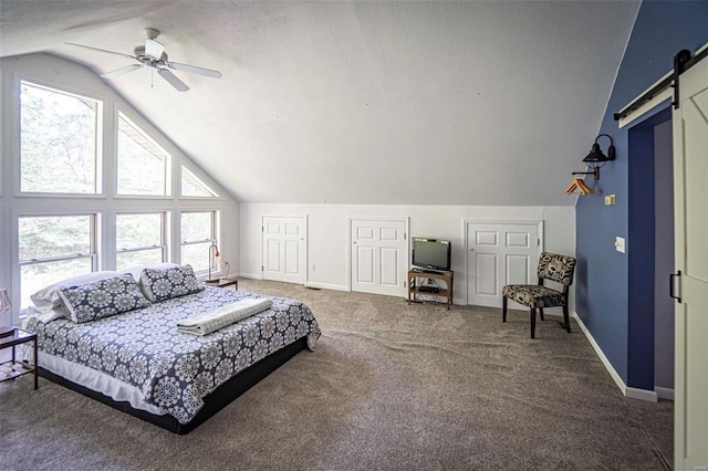 carpeted bedroom featuring a textured ceiling, a barn door, vaulted ceiling, and ceiling fan