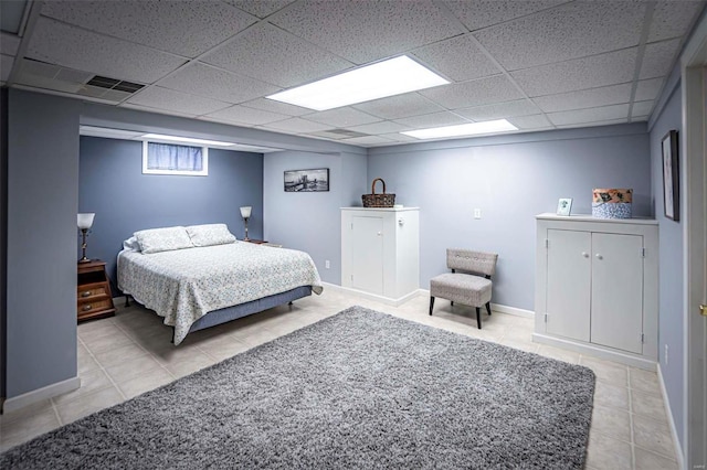 bedroom with a paneled ceiling and light tile patterned flooring